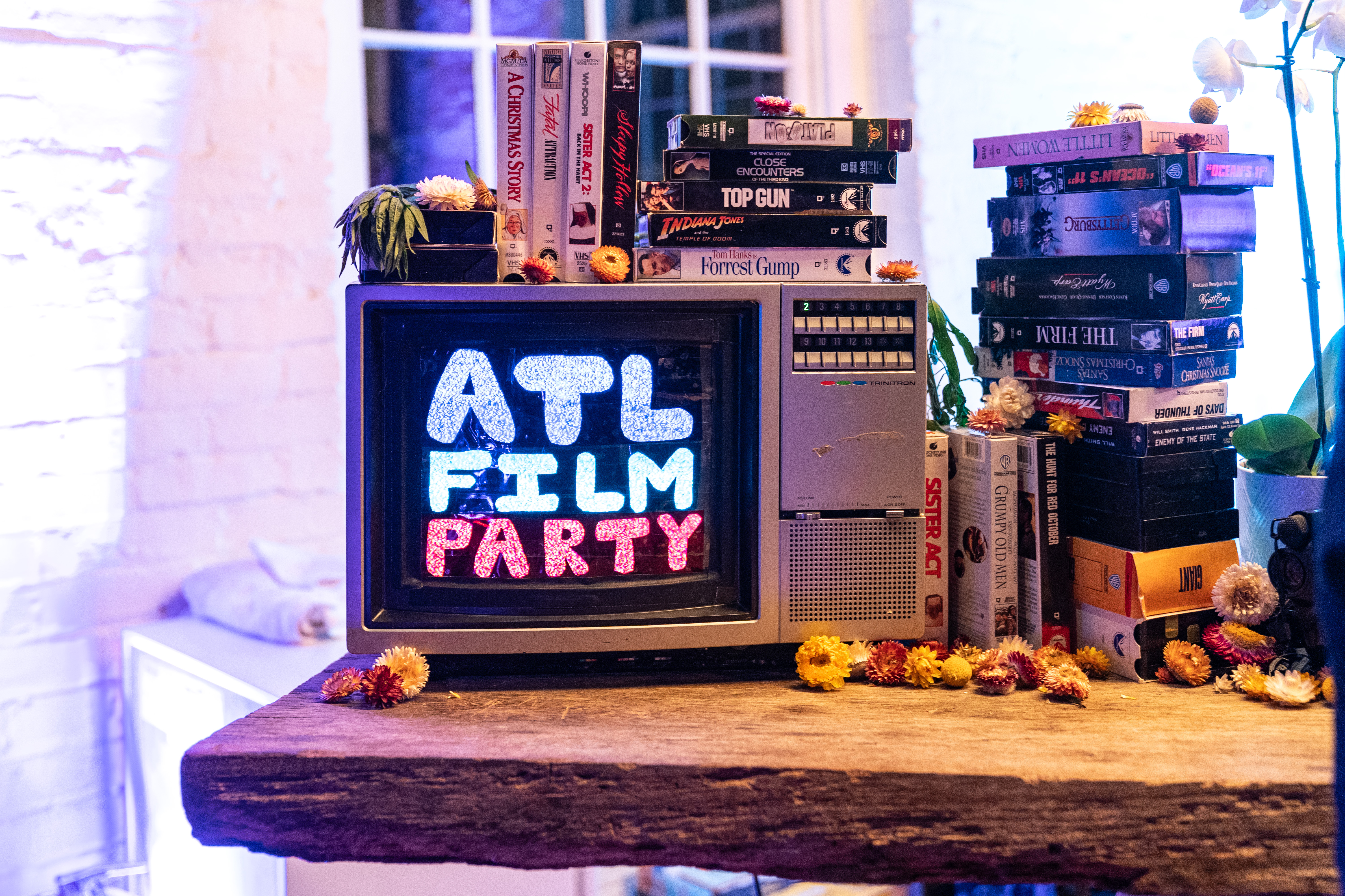 TV with ATL Film Party text on it and books stacked around it. A decorative setup for the bar at events.