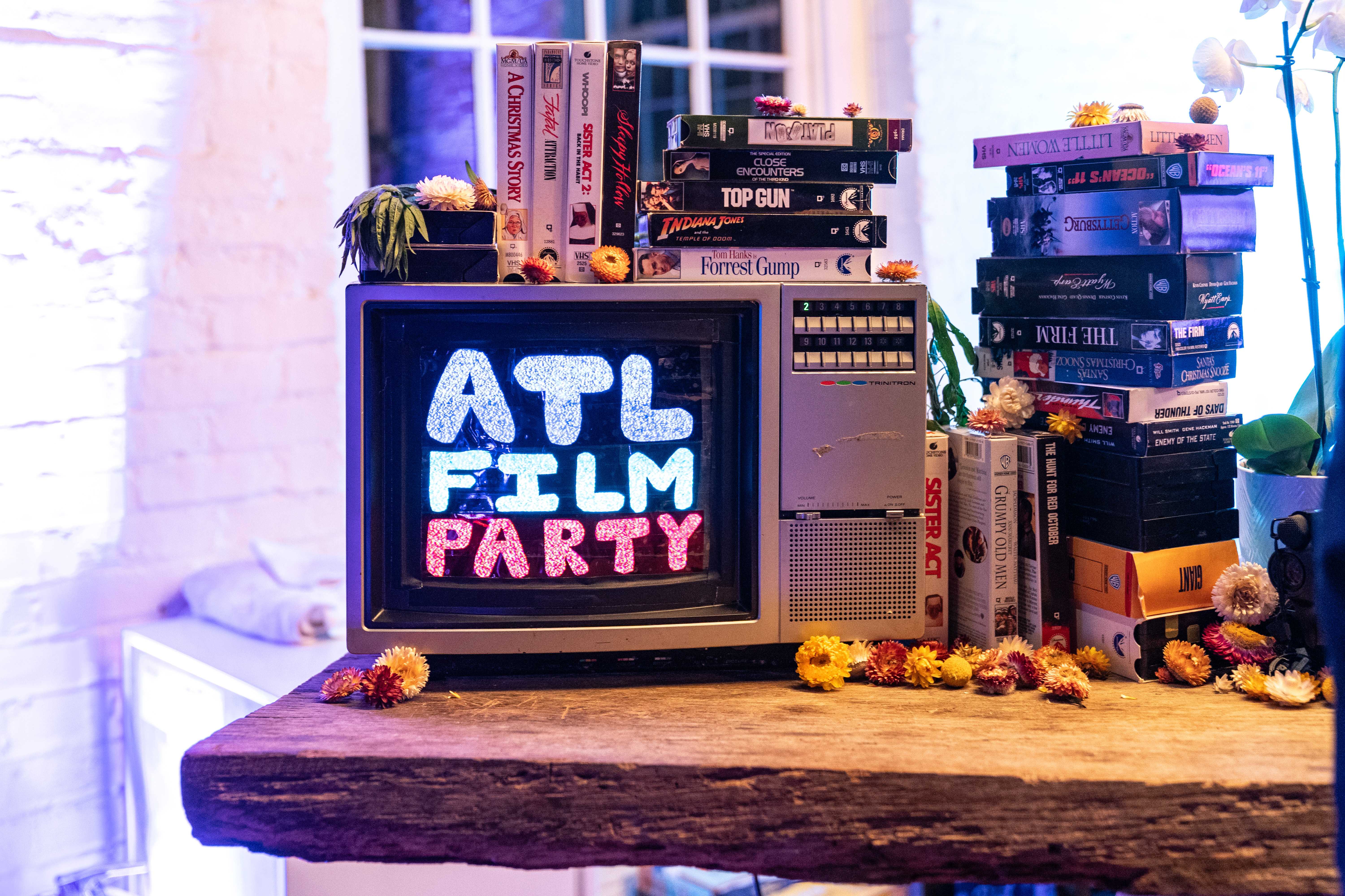 TV with ATL Film Party text on it and books stacked around it. A decorative setup for the bar at events.